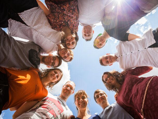 Junge Leute aus der Netzwerk Gemeinde stehen im Kreis und schauen von oben in die Kamera